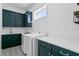 Laundry room with dark green cabinets, quartz countertops, and patterned floor at 13282 Bromborough Dr, Orlando, FL 32832