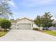 Tan house with gray double garage doors and a brick paver driveway at 1813 Pelican Hill Way, Poinciana, FL 34759