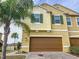 Two-story townhome with a brown garage door and landscaping at 272 Muscogee Ln, Orlando, FL 32825