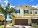 Inviting two-story home with a well-maintained lawn, lush palm tree, and a spacious two-car garage at 272 Muscogee Ln, Orlando, FL 32825