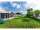 Expansive backyard with lush green grass, privacy fence, screened patio, and mature trees, perfect for outdoor enjoyment at 435 Madina Cir, Davenport, FL 33837