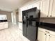 Spacious kitchen boasts white cabinets, black countertops, and a modern black refrigerator at 900 Shorehaven Drive, Poinciana, FL 34759