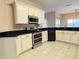 Modern kitchen with stainless steel appliances, double oven, white cabinets and sleek black countertops at 900 Shorehaven Drive, Poinciana, FL 34759