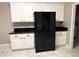 Bright kitchen featuring white cabinetry, black countertops, and a modern black refrigerator at 900 Shorehaven Drive, Poinciana, FL 34759