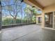 Enclosed patio featuring a smooth gray floor, screen enclosure, and a view of tropical landscaping at 900 Shorehaven Drive, Poinciana, FL 34759
