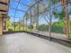 Spacious screened-in patio with tranquil backyard views of tropical trees, plants, and blue sky at 900 Shorehaven Drive, Poinciana, FL 34759