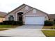 Tan house with white garage door and landscaping at 1068 Lake Berkley Dr, Kissimmee, FL 34746