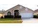 Tan house with white garage door and landscaping at 1068 Lake Berkley Dr, Kissimmee, FL 34746