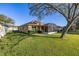 A well-maintained backyard featuring lush green grass, a screened-in lanai, and mature trees, creating a private outdoor space at 26622 Bull Run, Leesburg, FL 34748