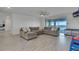 This modern living room has a large sectional couch, light wood floors, and sliding glass doors to the balcony at 820 Windlass Ct, Kissimmee, FL 34746