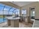 This covered outdoor kitchen has stone counters, a grill, a fridge, and views of the pool and sky at 820 Windlass Ct, Kissimmee, FL 34746