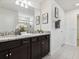 Bathroom vanity featuring granite countertop, dual sinks, and dark cabinetry at 1607 Kona Ln, Davenport, FL 33897