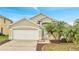 Tan house with white garage door, landscaping, and palm trees at 2318 Andrews Valley Dr, Kissimmee, FL 34758