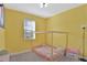 Bright bedroom featuring a simple wooden bed frame and yellow painted walls at 2587 Summer Star Way, Leesburg, FL 34748