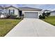Single-story home featuring a neutral color palette, complemented by a driveway, two-car garage, and low-maintenance landscaping at 2587 Summer Star Way, Leesburg, FL 34748