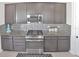 Gourmet kitchen featuring gray cabinets, granite countertops, and stainless steel appliances at 2587 Summer Star Way, Leesburg, FL 34748