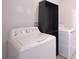 Bright laundry room with modern washing machine, dryer, and shelving at 2587 Summer Star Way, Leesburg, FL 34748
