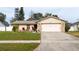 Tan one-story house with pink garage door and stone accents. Landscaped yard at 3618 Willow Lake Ct, St Cloud, FL 34769