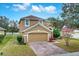 Tan two-story house with a brick paver driveway and landscaping at 4364 Fox Glen Loop, Kissimmee, FL 34746