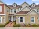 Tan two-story townhome with a brick walkway, landscaping, and two-car garage at 7591 Sunny Dreams Ln, Kissimmee, FL 34747