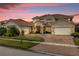 Two-story house with a three-car garage and brick driveway, under a beautiful sunset at 900 Windlass Ct, Kissimmee, FL 34746