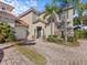 Tan two-story home with tile roof, paver driveway, and lush landscaping at 220 Brunello Dr, Davenport, FL 33897