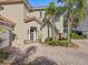 Two-story home with dark gray door and paver driveway, and palm trees at 220 Brunello Dr, Davenport, FL 33897
