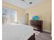 Main bedroom with king bed, dresser, and large window, showcasing natural light at 220 Brunello Dr, Davenport, FL 33897