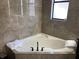 Bathroom featuring a corner soaking tub with tile surround and decorative towels at 3034 Boating Blvd, Kissimmee, FL 34746