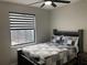 Cozy bedroom featuring a comfortable bed with a patterned quilt, ceiling fan, and natural light from the window at 3034 Boating Blvd, Kissimmee, FL 34746