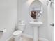 Small bathroom with pedestal sink, toilet, and oval mirror at 3074 White Horse Ct, Kissimmee, FL 34746