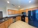 Kitchen with light wood cabinets, black appliances, and dark countertops at 6660 S Goldenrod Rd # 126B, Orlando, FL 32822