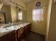 Double vanity bathroom with a window and wall-mounted light at 869 Colville Dr, Kissimmee, FL 34759