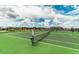 Tennis court with green surface and net at 9194 Sommerset Hills Dr, Davenport, FL 33896