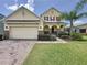 Two-story house with stone accents, a paved driveway, and a manicured lawn at 993 Suffolk Pl, Davenport, FL 33896