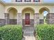 Elegant front porch with arched entryway, stone columns, and lush landscaping at 993 Suffolk Pl, Davenport, FL 33896