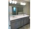 Double vanity bathroom with gray cabinets and a large mirror at 1144 Trappers Trail Loop, Davenport, FL 33896