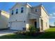 Two-story house with a beige exterior, two-car garage, and landscaping at 1144 Trappers Trail Loop, Davenport, FL 33896
