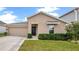 Tan house with black door, two-car garage, and manicured lawn at 1274 Fury St, Davenport, FL 33837