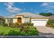Beautiful yellow house with a gray roof, white garage door, and lush landscaping at 135 Langham Dr, Davenport, FL 33897