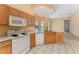Kitchen with wood cabinets, white appliances, and tiled floor at 135 Langham Dr, Davenport, FL 33897