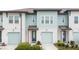Two-story townhome with light teal siding, two-car garage, and landscaping at 1481 Discovery St, Davenport, FL 33896