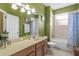 Bathroom with green walls, wood cabinets and bathtub shower combo at 2136 Laurel Blossom Cir, Ocoee, FL 34761