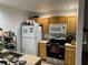 Small kitchen with wood cabinets, white appliances, and a microwave at 2200 San Christabolo Dr # 106, Kissimmee, FL 34741