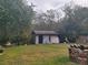 The backyard has a cute grey shed, lush greenery, and wood that is nestled in the trees at 4749 Hopespring Dr, Orlando, FL 32829