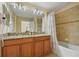Double vanity with granite countertop, large mirror, and bathtub at 8963 Coco Palm Rd, Kissimmee, FL 34747