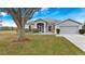 Single-story house with a large tree and well-maintained lawn at 103 Vega Ct, Davenport, FL 33896