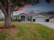 House exterior at dusk with a large oak tree at 103 Vega Ct, Davenport, FL 33896