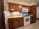 Kitchen with wood cabinets, white appliances, and floral wallpaper at 1186 Laguna Cir, St Cloud, FL 34771