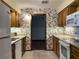 Kitchen features wood cabinets, floral wallpaper, and white appliances at 1186 Laguna Cir, St Cloud, FL 34771